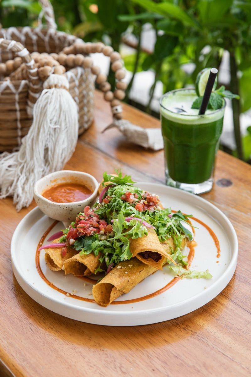 Plant Beef Taquitos and a green juice on an outdoor table